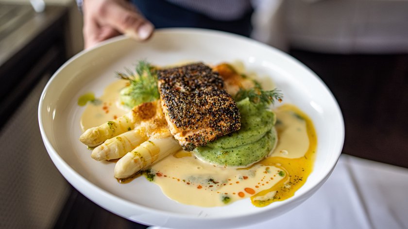 Genussvoll in den Frühling Gegrilltes Lachsfilet mit weißem Spargel und Sauce auf weißem Teller