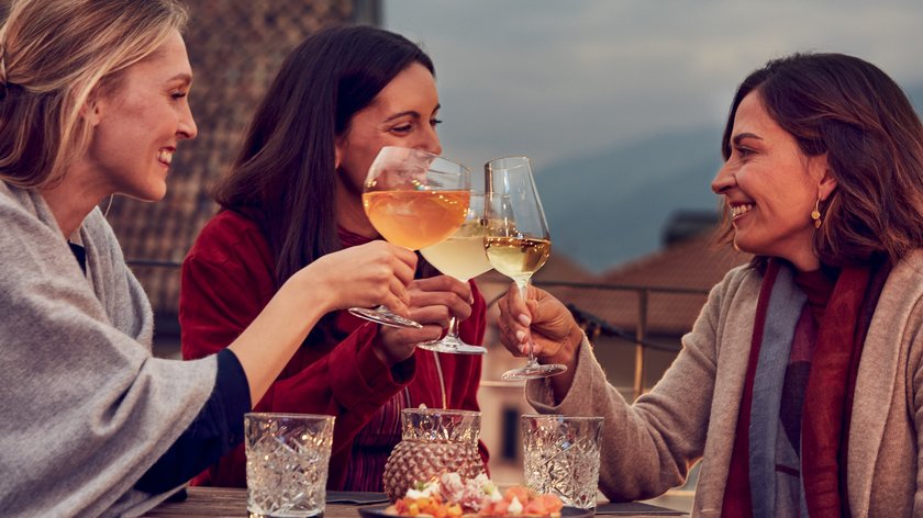 Zeit für einen Aperitivo Drei Frauen stoßen mit Weingläsern bei einem Treffen im Freien an