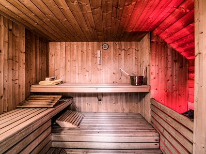 Explorer and wellness hotel near Sterzing Wooden sauna with red lighting, bucket and towels