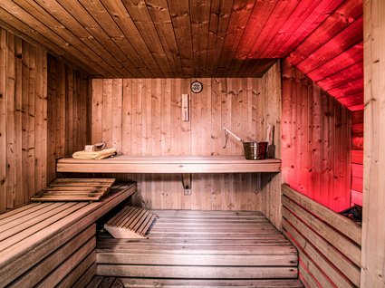 Rilassarsi da Gudrun Sauna in legno con illuminazione rossa, secchio e asciugamani