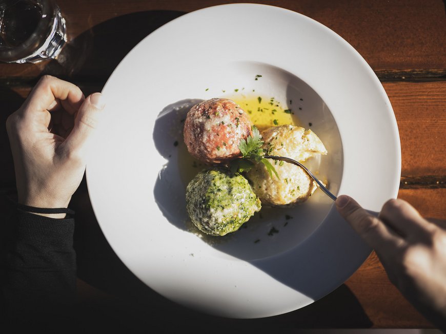 The Ladurns ski area and other winter highlights Three colorful dumplings on a white plate with fork and glass of water