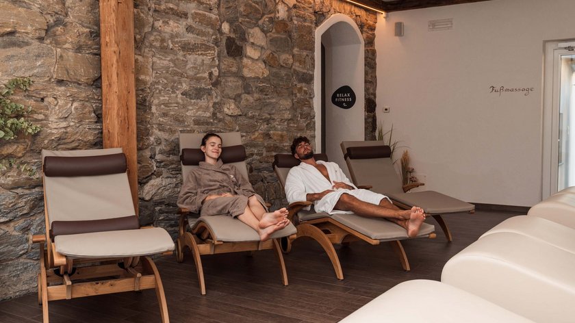 Gudrun liebt: den November Zwei Personen entspannen auf Liegestühlen in einem Spa-Ruheraum vor Steinmauer