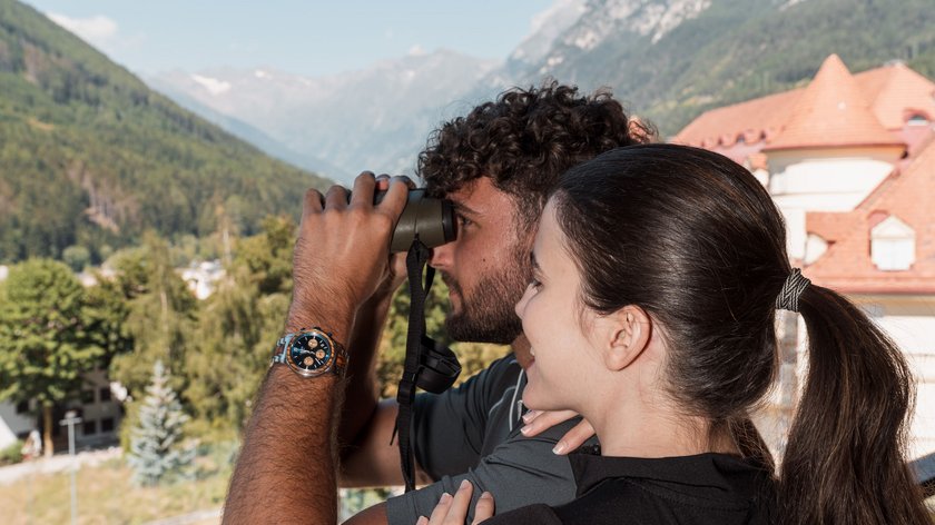 Un urrà a tutti i papà! Coppia che osserva il paesaggio con il binocolo in montagna