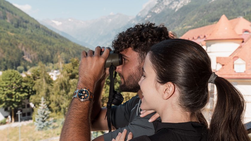 Ein Hoch auf die Papis! Paar beobachtet Landschaft mit Fernglas in den Bergen