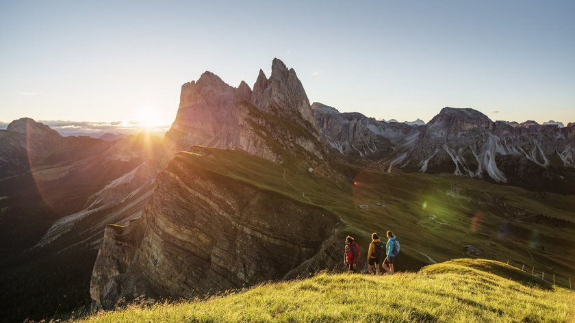 Aria fresca da Gudrun Tre escursionisti su collina verde con tramonto e panorama montano