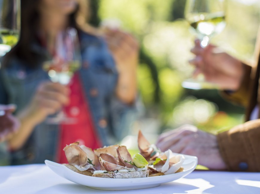Hotel between Brenner and Sterzing: events Plate of appetizers with meat and people holding wine glasses in the background