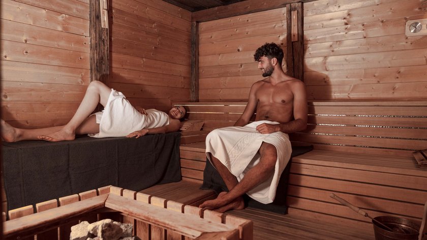 Sauna alle erbe aromatiche Uomo e donna rilassati in una sauna finlandese con pareti di legno