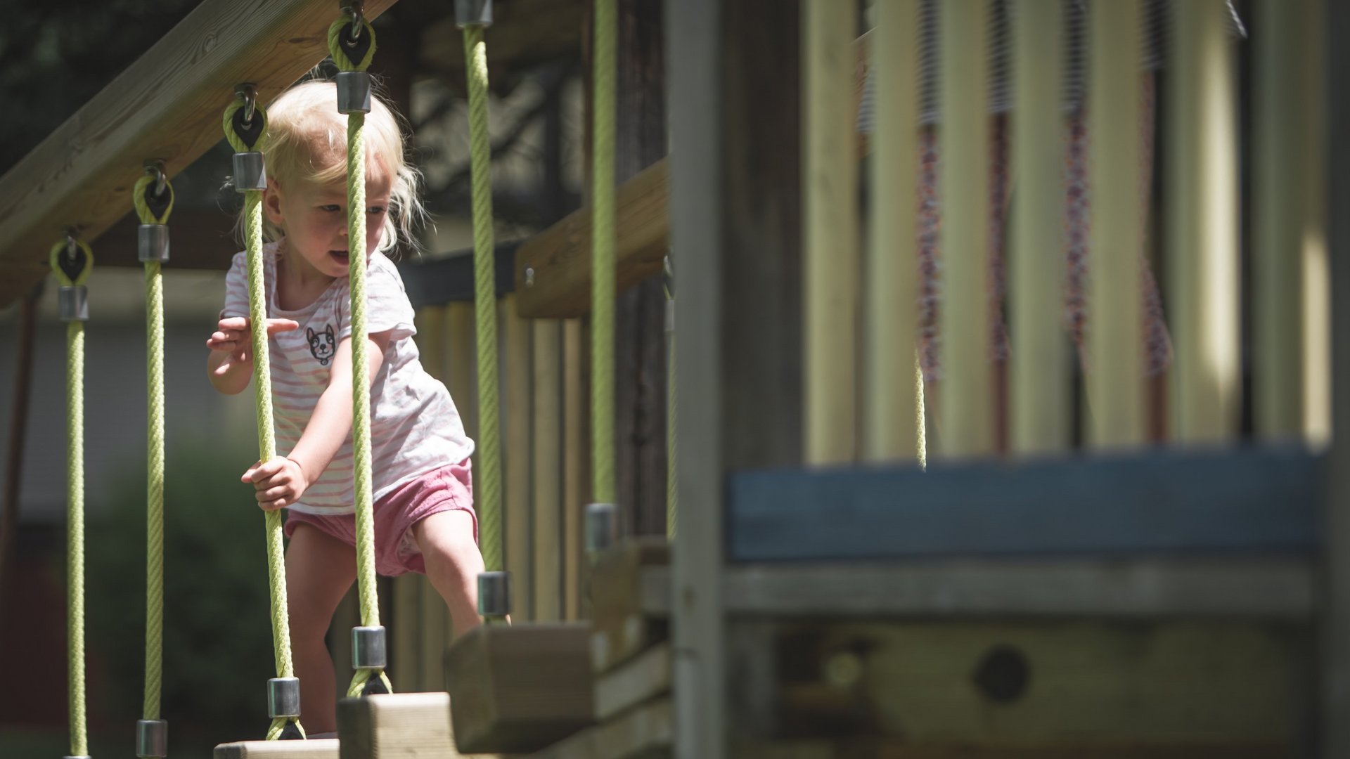 Hotel a Ladurns per famiglie Bambina che scala una struttura a corde in un parco giochi all'aperto