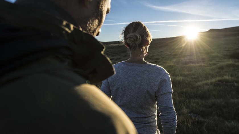 Dolomieu-Weg Zwei Personen schauen in den Sonnenuntergang auf einer Wiese