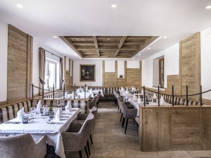 Gudrun in Gossensass: hotel with heart Elegant restaurant with wooden walls and tables set with white tablecloths