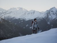 Gudrun in Gossensass: hotel with heart Woman hiking with backpack and poles in snowy mountain landscape