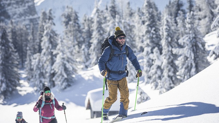 Purer Wintergenuss Drei Menschen wandern mit Schneeschuhen im verschneiten Gebirge