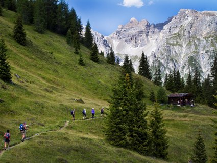 Gudrun in Gossensass: Hotel mit Herz Wanderer auf Pfad in grüner Berglandschaft mit Hütte und Felsen im Hintergrund