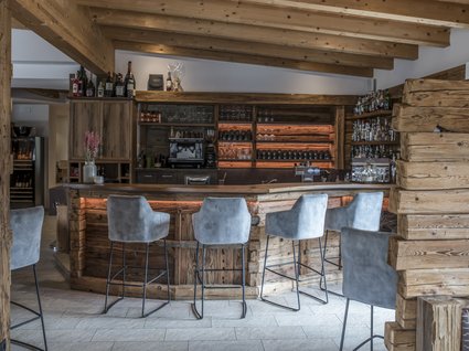 Gudrun in Gossensass: hotel with heart Cozy bar with wooden counter and gray bar stools in rustic style