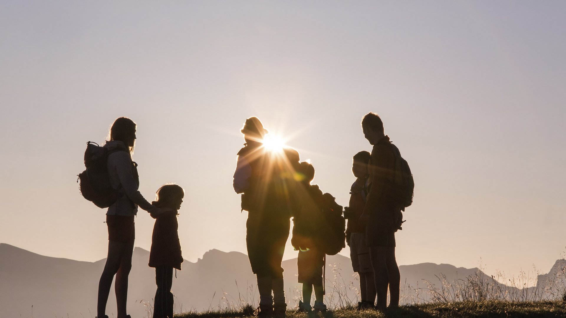 Hotel in Val di Fleres: gli eventi Sagome di famiglia con zaini al tramonto in montagna