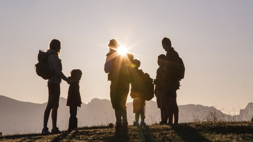 Sonnenaufgangswanderung auf den Rosskopf Silhouetten einer Familie mit Rucksäcken bei Sonnenuntergang in den Bergen