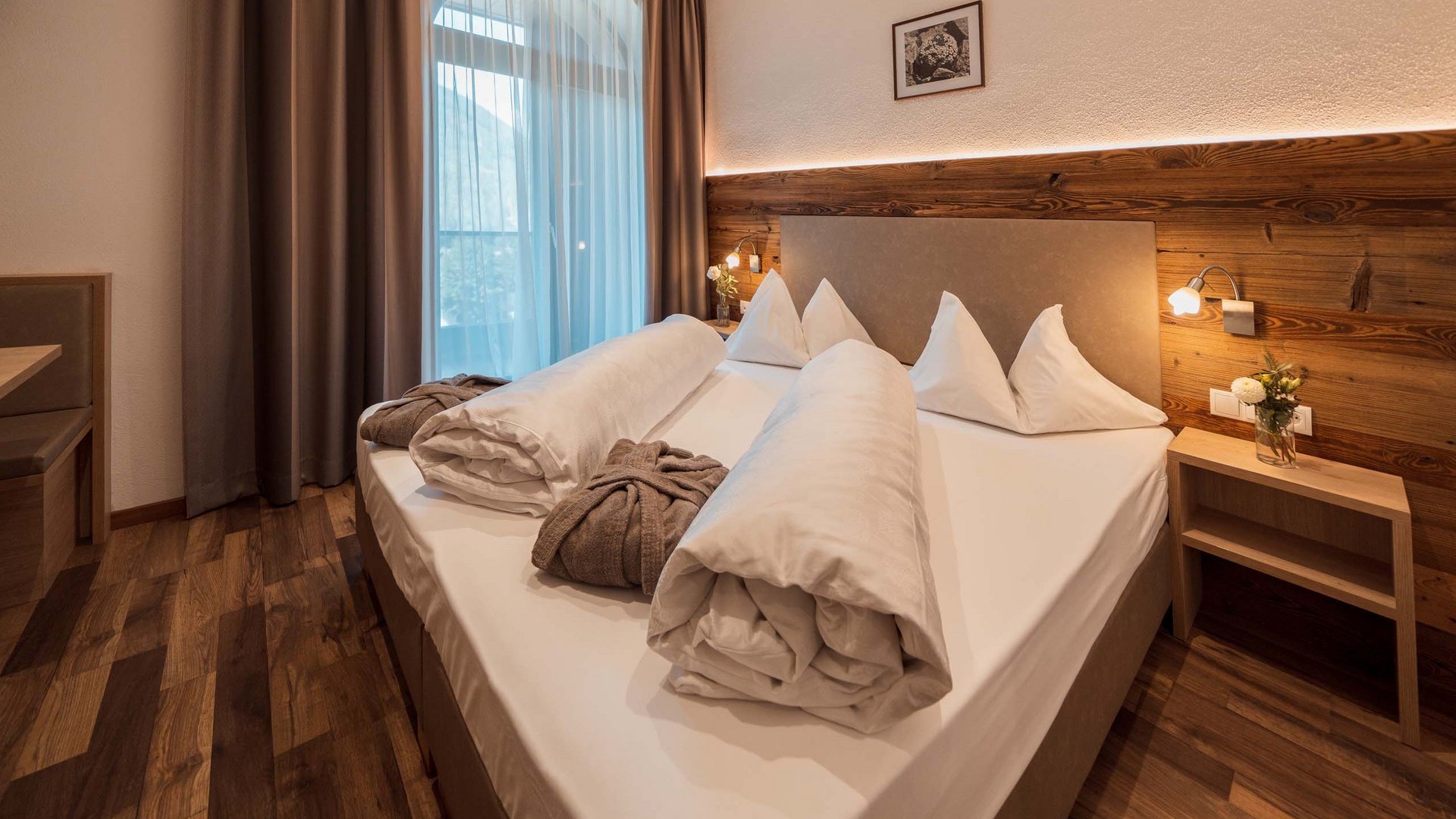 Home Camera d'hotel moderna con letto matrimoniale, decorazioni in legno e finestre con tende coprenti