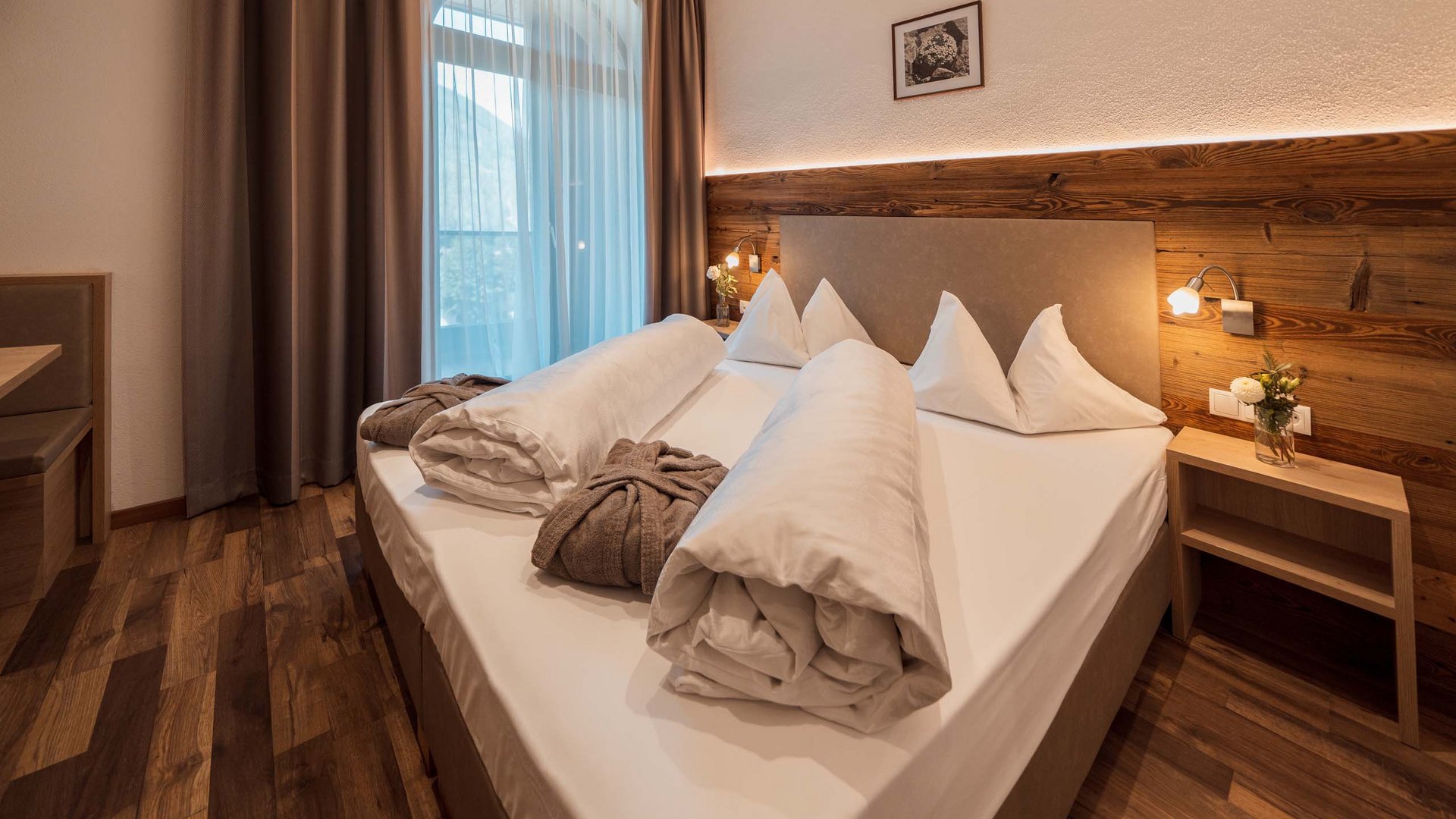 Gudrun in Gossensass: hotel with heart Modern hotel room with double bed, wood decor, and window with sheer and blackout curtains