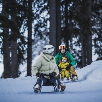 Gudruns Blog: alles über Sterzing, übers Wandern, über Tirol Personen rodeln im Schnee mit Kind in winterlicher Waldlandschaft