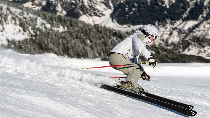 Drei auf einen Streich Person fährt Ski auf schneebedecktem Berghang bei klarem Wetter