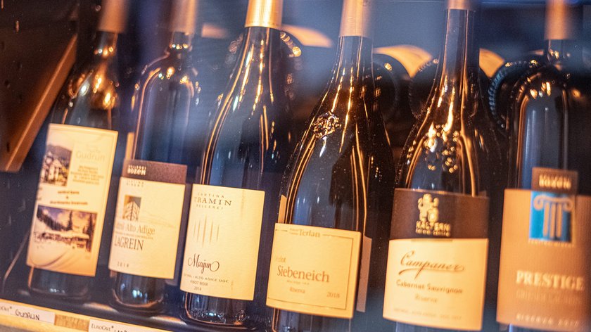 Vi va un bicchiere di vino? Bottiglie di vino diverse in un frigorifero per vini affiancate