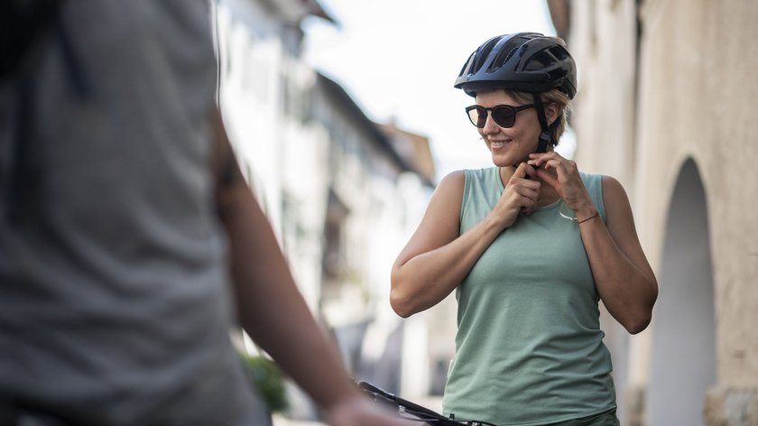 Von München nach Venedig mit dem Rad Frau mit Fahrradhelm und Sonnenbrille macht Fahrradtourbereit