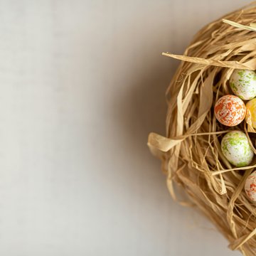 Home Uova di Pasqua colorate in un nido di paglia su sfondo chiaro