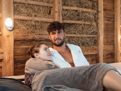 Gudrun in Gossensass: hotel with heart Couple in robes relaxing in wooden sauna with straw walls
