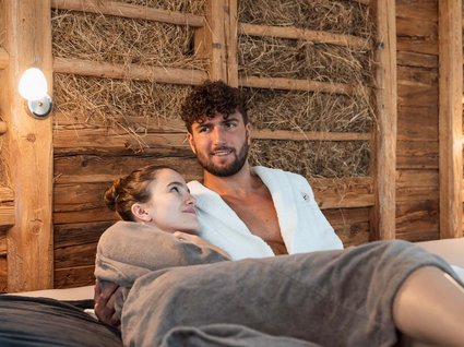 Home Coppia in accappatoi rilassata in una sauna di legno con pareti di paglia