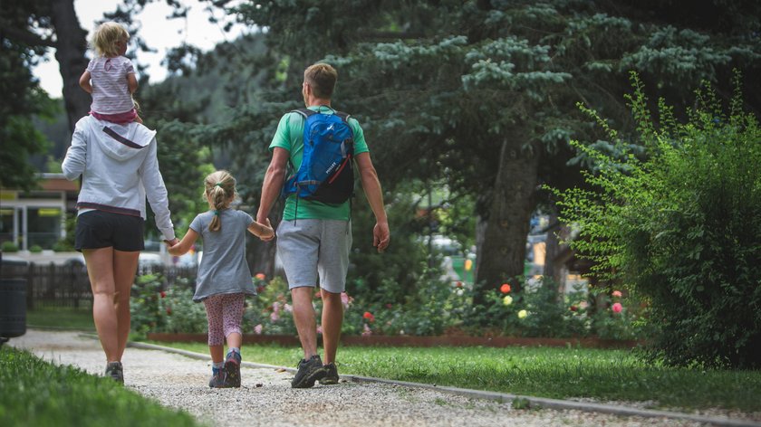 Ausflugsziele für Familien Familie mit zwei Kindern geht im Park auf einem Kiesweg spazieren