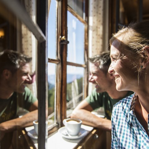 Hiking in Sterzing and the surrounding area Woman and man smiling by a sunny window with coffee