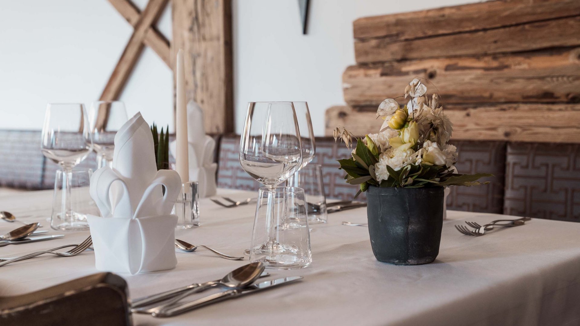 Unterkunft im Wipptal: Essen bei Gudrun Gedeckter Tisch mit Servietten, Weingläsern und Blumenarrangement im Restaurant