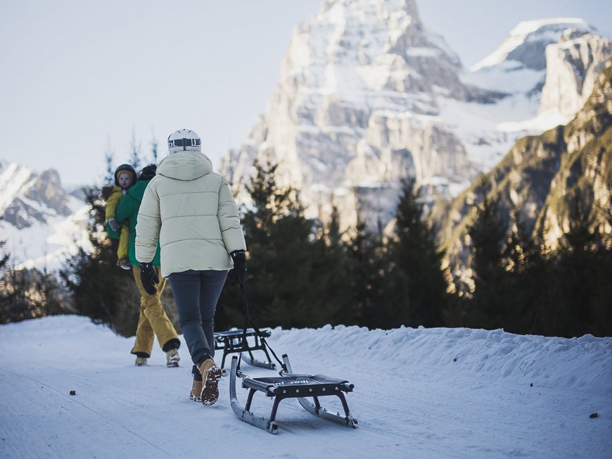 Hotel in Gossensass: welcome to Gudrun! Person pulling sled on snowy path with mountain in the background