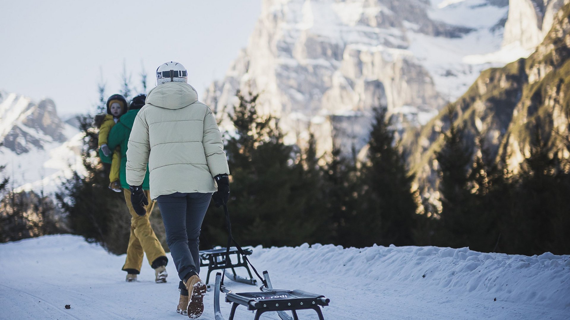 Hotel a Ladurns per famiglie Persona che trascina una slitta su sentiero innevato con montagna sullo sfondo