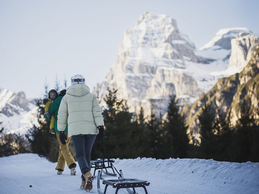 Hotel in Gossensass: welcome to Gudrun! Person zieht Schlitten auf verschneitem Weg mit Berg im Hintergrund