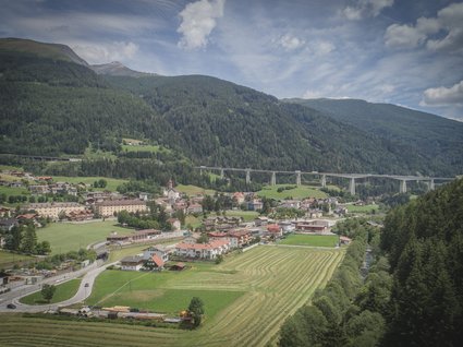 Gudrun in Gossensass: Hotel mit Herz Dorf am Fuße bewaldeter Berge mit Brücke und Feldern im Tal