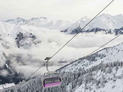 Home Seggiovia su montagne innevate e pendii coperti di alberi