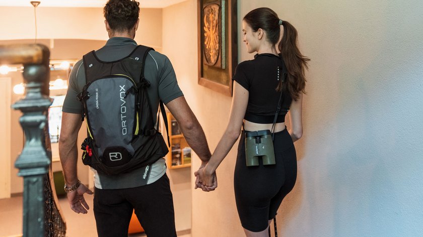 Ein einmaliges Naturschauspiel Paar mit Wanderrucksack und Fernglas hält Händchen und geht Treppe hinunter