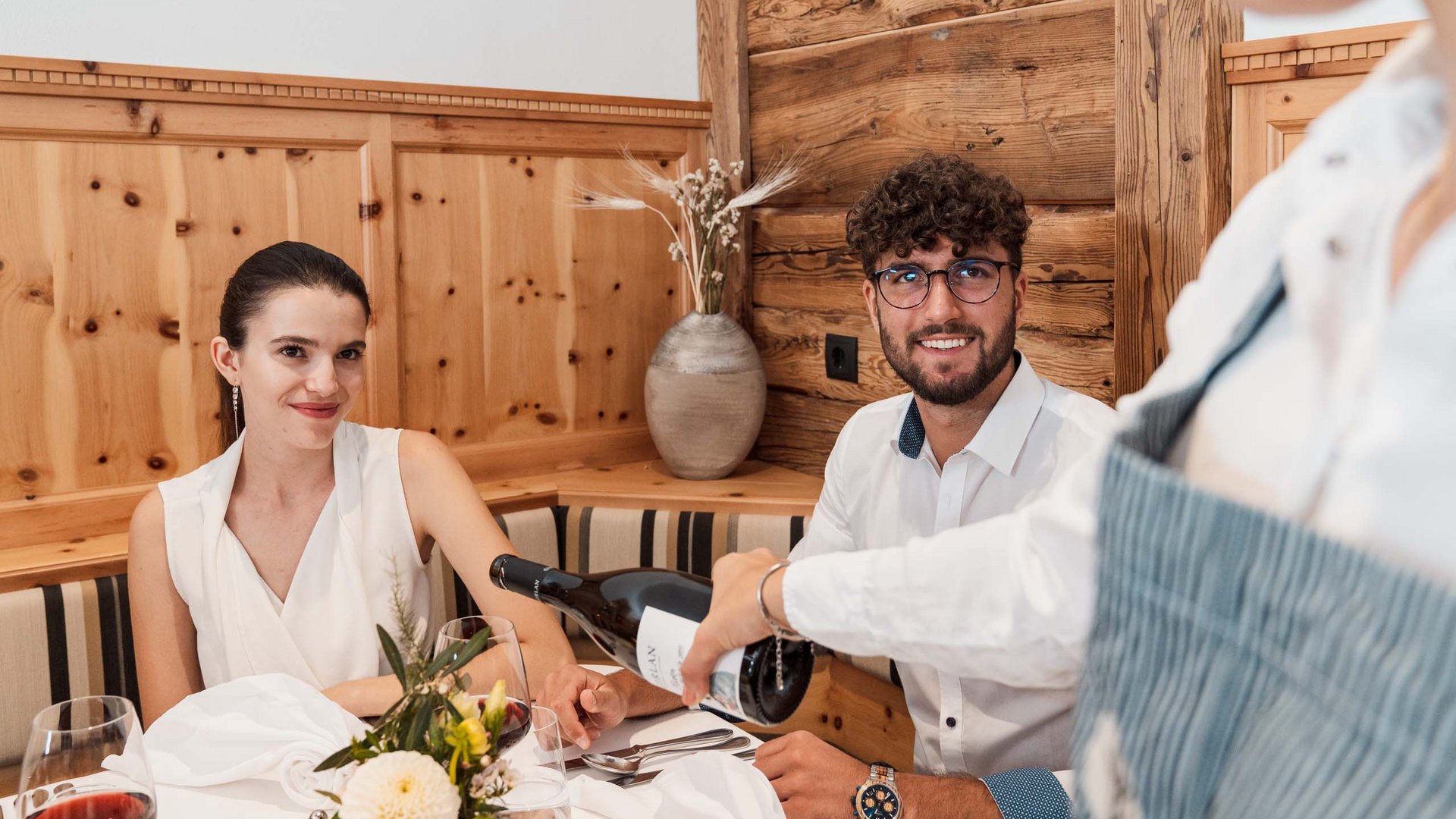 Hotel a Colle Isarco: benvenuti da Gudrun! Coppia al ristorante con cameriera che versa vino al tavolo
