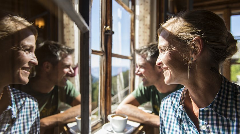 activeCARD Uomo e donna godono del caffè vicino alla finestra con vista montagne