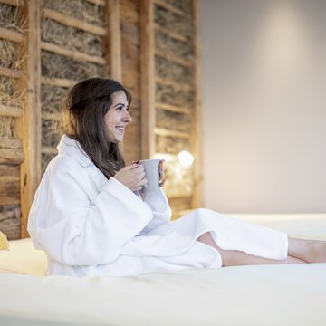 Gudruns Blog: alles über Sterzing, übers Wandern, über Tirol Frau im Bademantel entspannt mit Tasse auf einem Bett in einem gemütlichen Raum