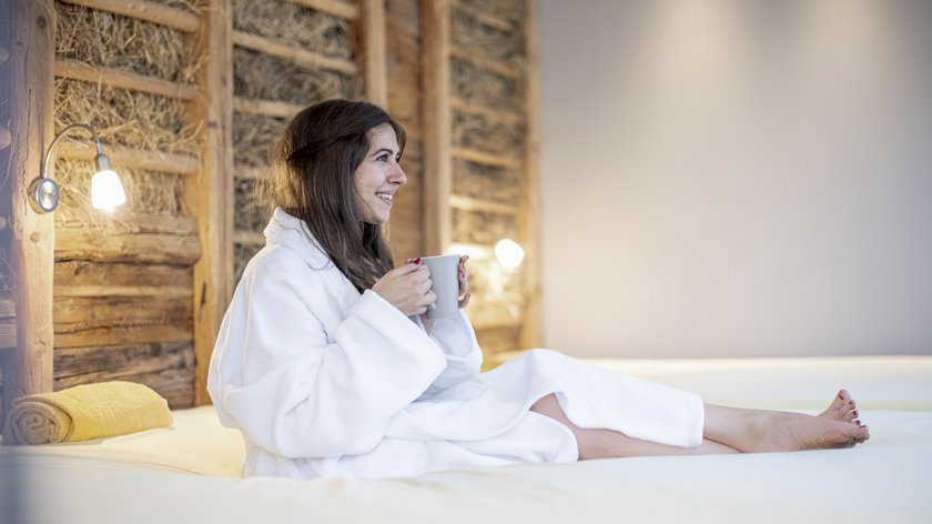 Pasqua da Gudrun Donna in accappatoio bianco rilassata con tazza su un letto in stanza accogliente