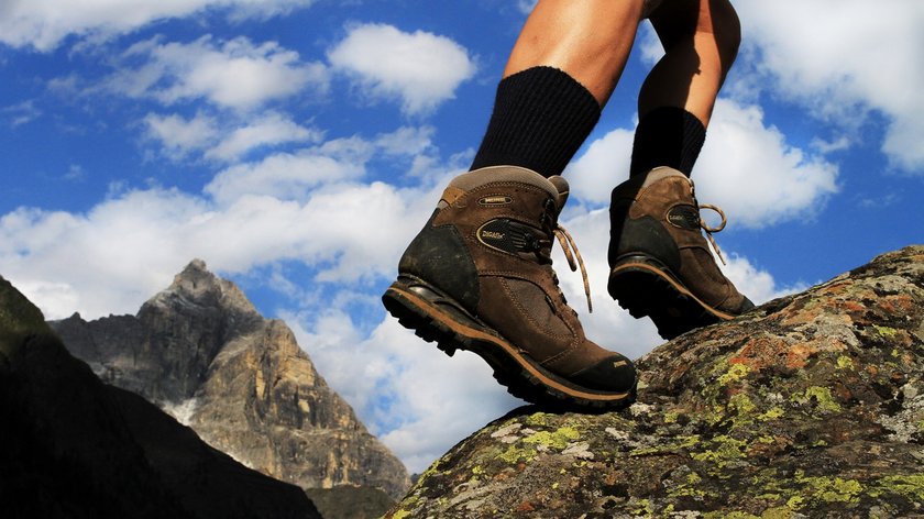 Ein einzigartiges Wandererlebnis Wanderer mit braunen Wanderschuhen auf felsigem Gelände vor Bergkulisse