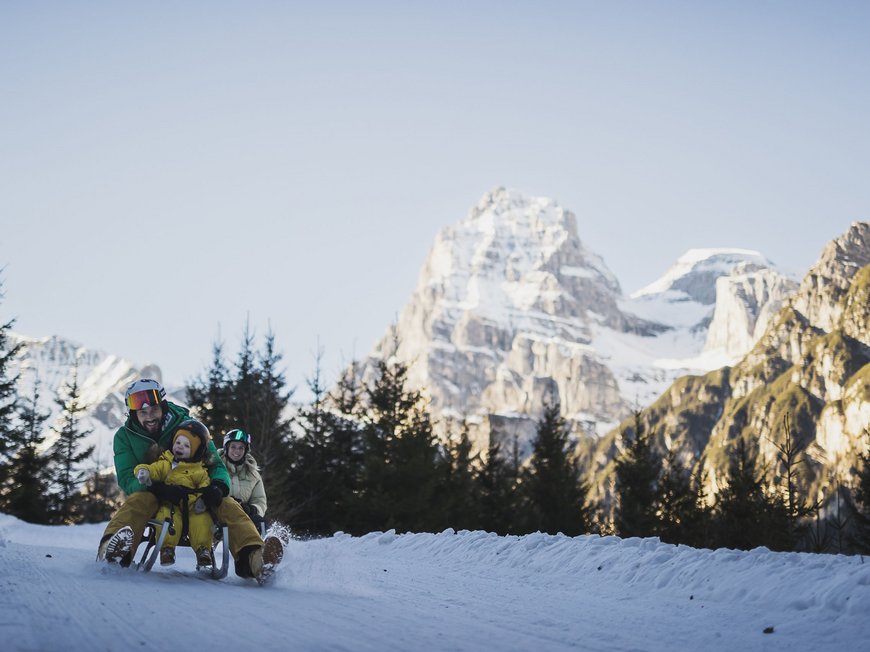 The Ladurns ski area and other winter highlights Family enjoying sled ride on snow with mountain background