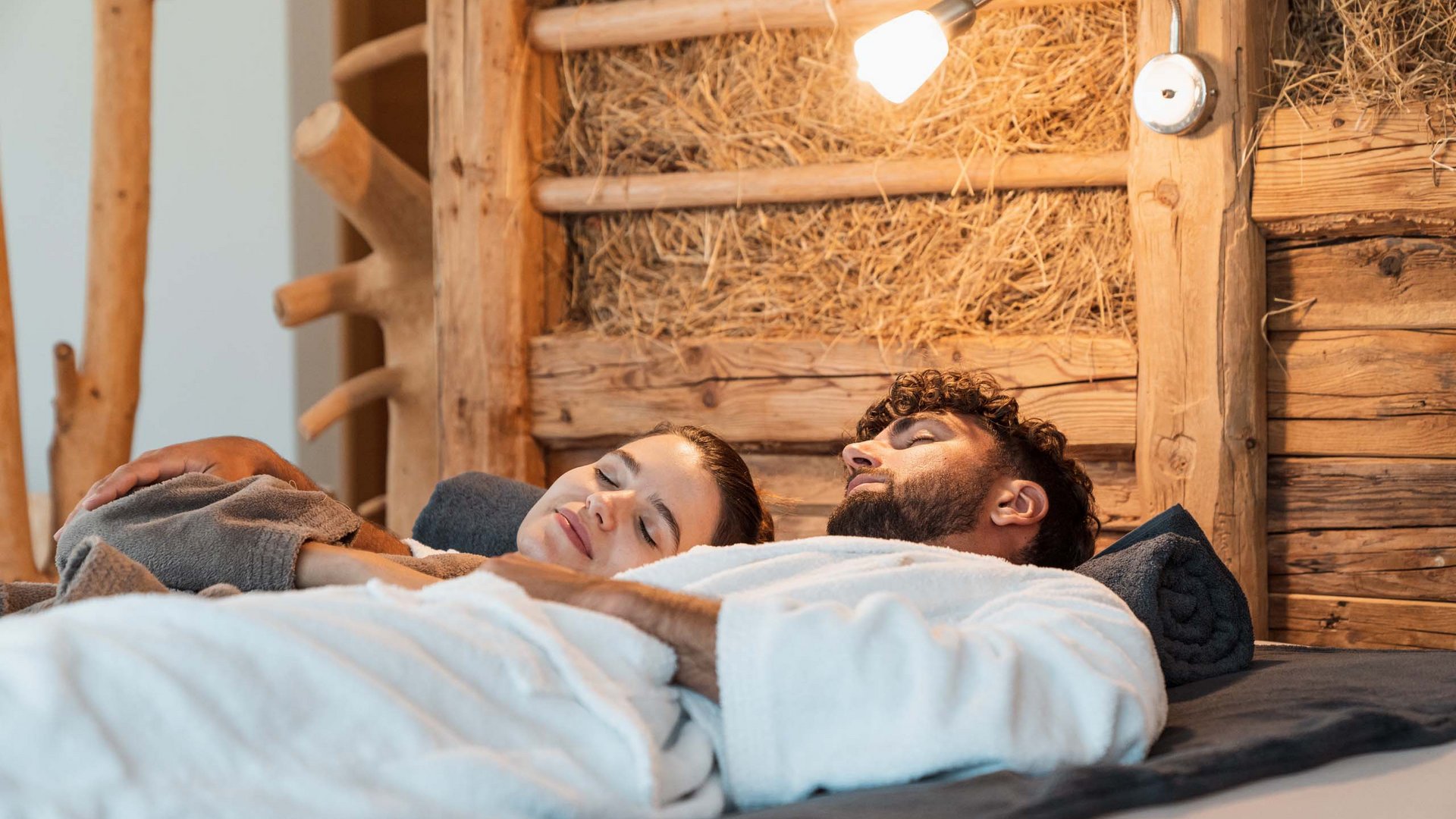 Hotel a Colle Isarco: benvenuti da Gudrun! Coppia rilassata in accappatoi che riposa in una stanza rustica