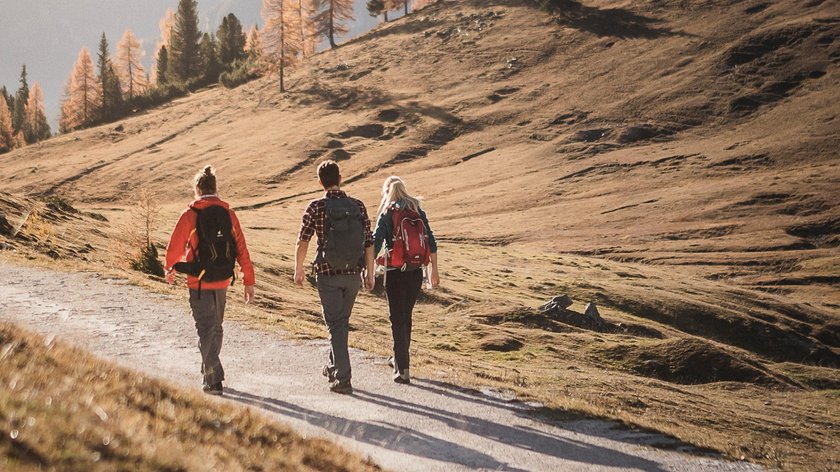 Festa di San Martino Tre escursionisti con zaini su sentiero di montagna in autunno