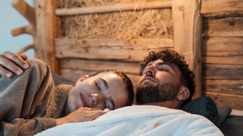 Ausflüge für Verliebte Paar in Bademänteln entspannt liegen auf Holzwand Hintergrund