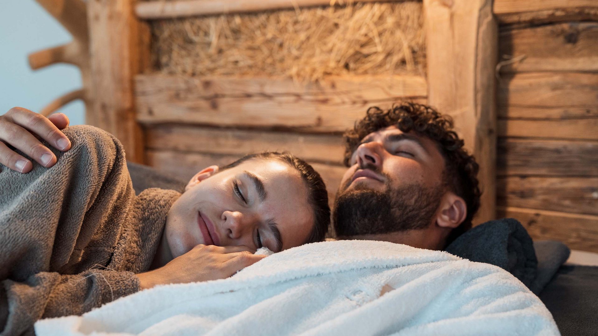Eines der coolsten Hotels in Gossensass (Südtirol) Paar in Bademänteln entspannt liegen auf Holzwand Hintergrund